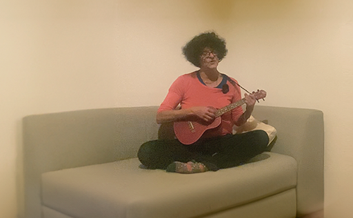 Frau mit Ukulele auf Sofa sitzend